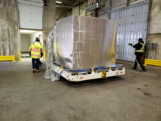 Le personnel emballe les boîtes de porc réfrigéré dans des plaques thermiques pour maintenir la température froide à l'aéroport international d'Edmonton