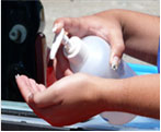 Close up photograph of a person dispensing hand sanitizer into their palm