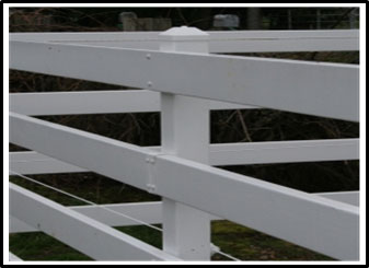 Photo d'une clôture pour enclos à chevaux en bois recouvert de polymère. Un cordon de clôture électrique est attaché aux poteaux intérieurs.