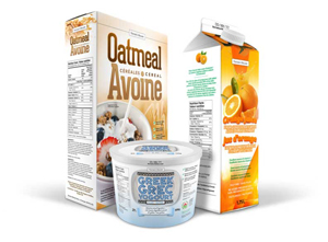 Un contenant de 500 grammes de yogourt grec à l'avant avec une boîte de céréales d'avoine à gauche et un carton de 1,25 litre de jus d'orange à droite. 