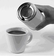 Image of someone pouring sirop from the tin can into a cup of coffee.
