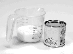 Image of milk in a measuring cup and a tin can beside it.