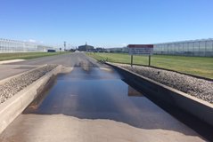 Une photo d'une voie d'accès avec une flaque de solution de lavage pour roues dans le milieu.
